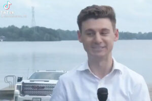 生放送中のレポーターの後ろで、車が湖に沈んでいく