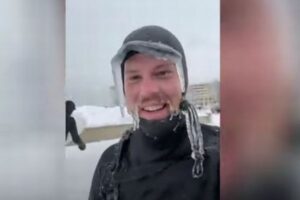 極寒の中でサーフィンする男性、髭やウェットスーツも凍りつく