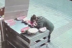 ロンドンの八百屋で、女がスイカにかぶりつき、そのまま去っていく