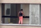 恐れ知らずの女性、安全具も身に着けず、高層マンションの縁で窓を拭く