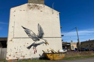 バンクシーの絵と一緒に置かれた容器、人々がゴミを捨てるため撤去に