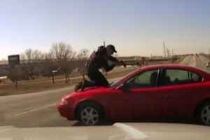 米警官、容疑者の車のボンネットに乗り、銃を構える【動画】