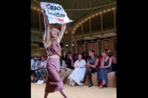 「Coach」のショーで、革製品の使用に抗議する女性がランウェイを歩く
