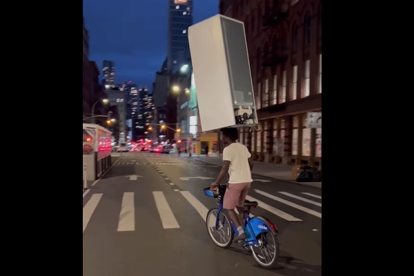 冷蔵庫を頭に載せて自転車で運ぶ男性、ニューヨークで撮影される