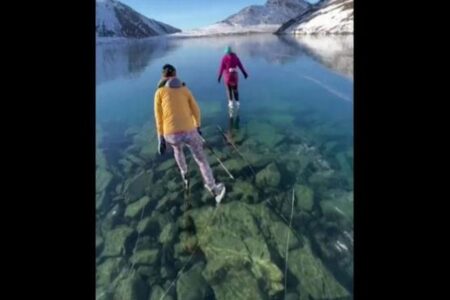 湖底が見えるほど透明な氷の上でスケート、アラスカの湖で撮影