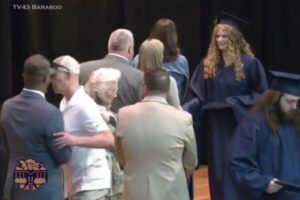 米高校の卒業式、白人の親が黒人の学区長を押しやる、娘と握手をさせないため
