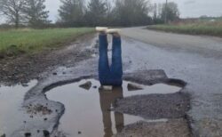 道路の陥没にうんざりした男性、水たまりに足の人形を置く【イギリス】