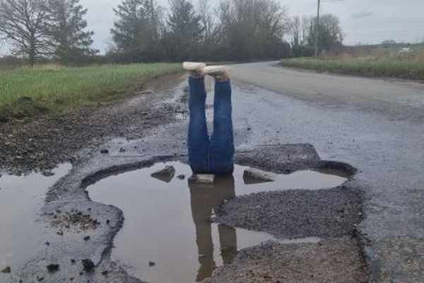 道路の陥没にうんざりした男性、水たまりに足の人形を置く【イギリス】