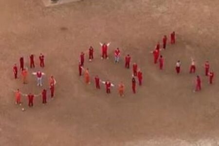 拘留された移民が並んで「SOS」の文字を形作り、助けを求める