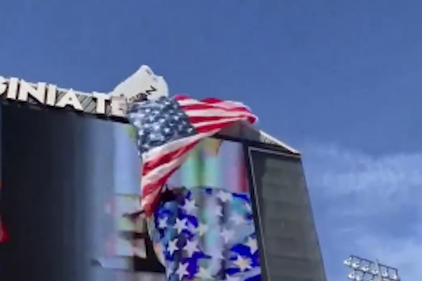 スタジアムのスコアボードにパラシュートが引っかかり、男性が宙吊りに